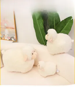 Plush white sheep dolls in three different sizes displayed on a comfortable beige sofa
