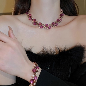 Detail of vintage necklace and bracelet set with magenta gems and gold diamond-encrusted floral