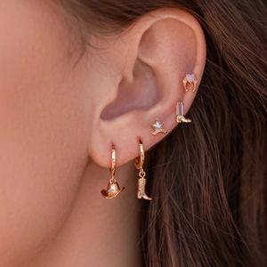 Close-up of rose gold cowboy boots and sheriff star earrings with blue zircon stones