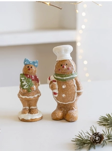 Close-up of resin gingerbread man couple ornaments with festive glitter finish and pine cones