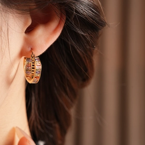 Close-up of vintage golden hoop earrings with colorful rectangle crystals on model