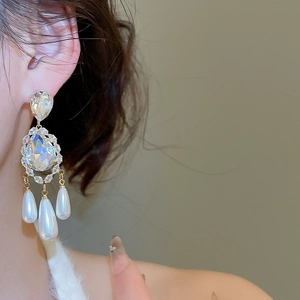 Detailed close-up of vintage style pearl earrings with zircon and silver needles