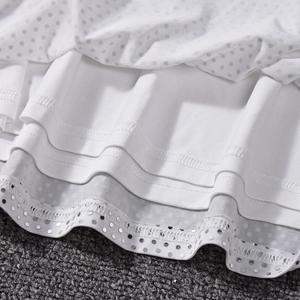 Détail d'une robe blanche en maille avec volants et bordure pailletée argentée brillante