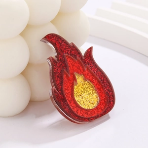 Macro shot of acrylic flame brooch with red and yellow glitter finish on white prop