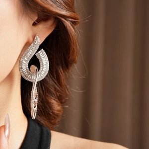 Close-up of leaf-shaped silver earrings with sparkling baguette and round zircon stones