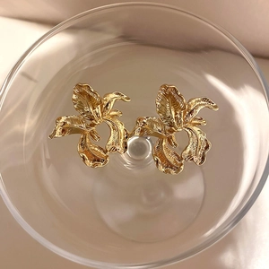 Macro shot of gold floral earrings with vintage texture in an artistic glass bowl