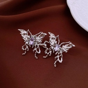 Détail d'une boucle de taille papillon argentée avec gemme violette sur tissu