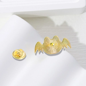 Back view of gold metal Halloween brooch on white geometric stand with butterfly clutch