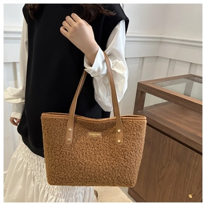 Close-up of brown faux shearling tote bag featuring leather handles and gold metal logo