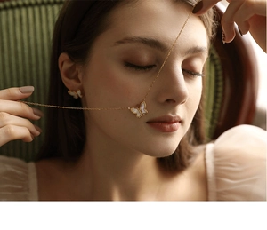 Close-up of golden butterfly necklace and earrings set with white mother of pearl