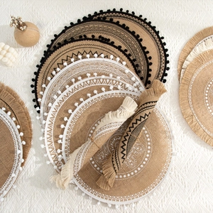 Detail of round woven jute placemats with bohemian fringe and black geometric patterns