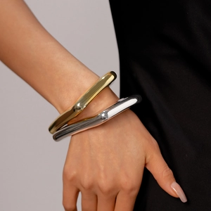 Minimalist metallic geometric open bracelets in gold and silver finish on a model's wrist