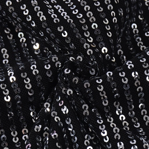 Vue macro de paillettes argentées sur tissu mesh noir montrant la texture détaillée