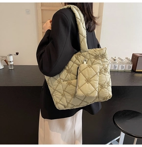 Close-up of light green quilted tote bag with floral embroidery and small zipper pouch