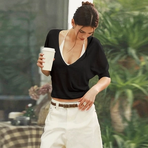 Detailed view of women's black deep V-neck short sleeve top layered over a white camisole