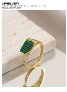 Gros plan d'une bague ajustable dorée avec pierre de malachite sur un support en pierre