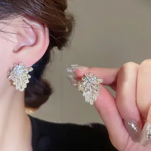 Elegant silver leaf stud earrings with sparkling zircon crystals on a model's ear