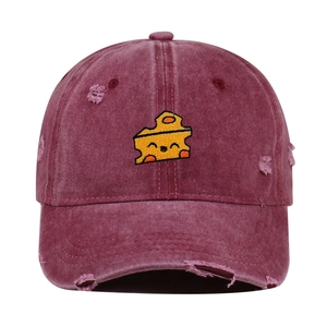 Close-up of cheese embroidery and distressed ripped details on a burgundy washed cotton cap