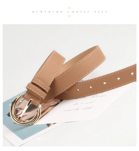 Detail of camel brown faux leather belt featuring white stitching and gold round buckle