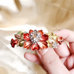 Vintage hair clip with red enamel flowers and sparkling crystals on golden metal base