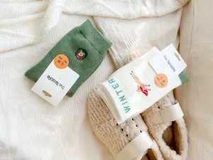 Detail of forest green and off-white thick winter socks with reindeer embroidery