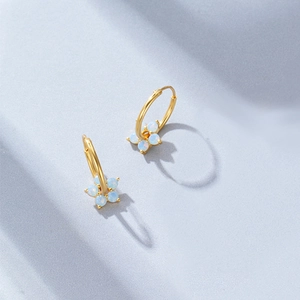 Detailed shot of golden s925 silver hoop earrings with blue opal flower charms