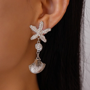 Detailed close-up of silver starfish and seashell earrings worn on model with dark hair