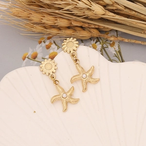 Golden sunflower earrings with starfish pearl charms on a decorative white shell tray
