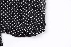 Detail of black chiffon fabric featuring white polka dots and delicate pleated stitching