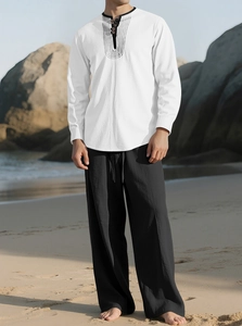 Men's white linen long sleeve shirt with embroidery and black wide leg pants on the beach