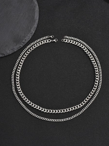 Close-up of double layer silver Cuban chain necklace on dark textured rock background