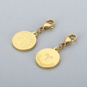 Close-up of gold stainless steel Libra and Courageous zodiac charms on grey background