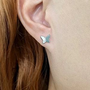 Close-up of minimalist S925 sterling silver butterfly stud earring on a female ear model