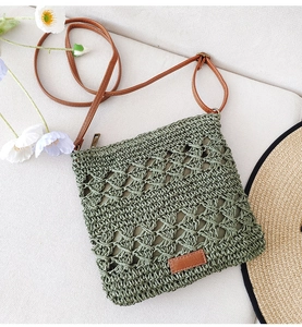 Detail of green hand-woven paper rope bag with brown leather strap and metal zipper