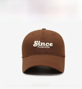 Close-up of white Since FASHION embroidery on a dark brown cotton baseball cap