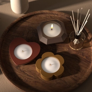 Set aus Herz-, Blumen- und geometrischen Kerzenhaltern mit brennenden Holzdochten im Tablett