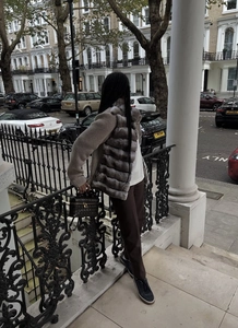 Vue détaillée de la texture du gilet en fourrure grise avec un tricot marron en extérieur