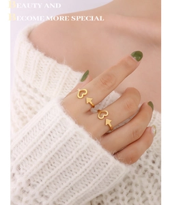 Detail of adjustable heart and arrow rings in 18K gold plated finish worn on finger