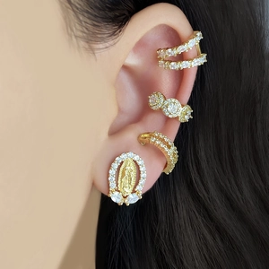 Close-up of golden 18K gold-plated Virgin Mary stud earrings and micro-paved zircon ear cuffs