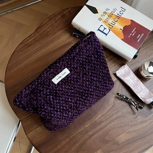 Purple tweed textured cosmetic bag with simple wish label on a rustic wooden table