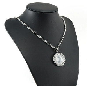 Detailed view of silver necklace with Virgin Mary pendant on black mannequin stand