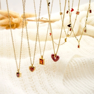 Vertical display of heart-shaped red zircon necklaces on a cream knit background