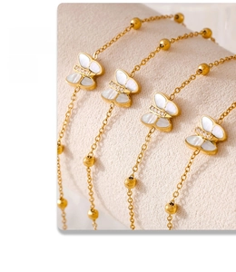 Macro detail of butterfly charms in white mother-of-pearl and 18k gold plated steel