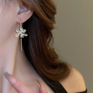 Detail view of silver iris flower earrings with elegant long drops on a female model