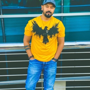 Detail of a yellow T-shirt featuring a black eagle print worn by a male model outdoors