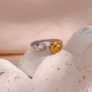 Close-up of dual-tone gold and silver open ring with organic droplet fluid design