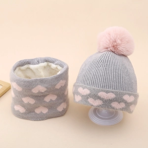 Detail of gray knitted hat and scarf set with pink heart pattern and fleece lining