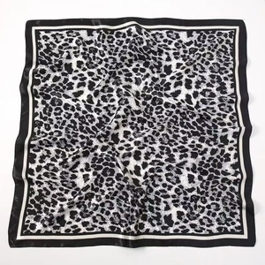 Macro detail of square leopard print silk scarf with satin texture and double borders