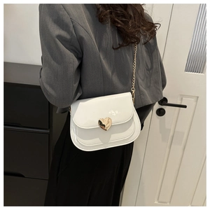 Detail of white patent saddle bag featuring a gold heart buckle and elegant chain strap
