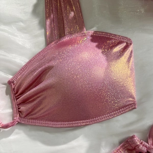 Detailed macro view of shiny metallic pink bikini top with gold glitter fabric texture